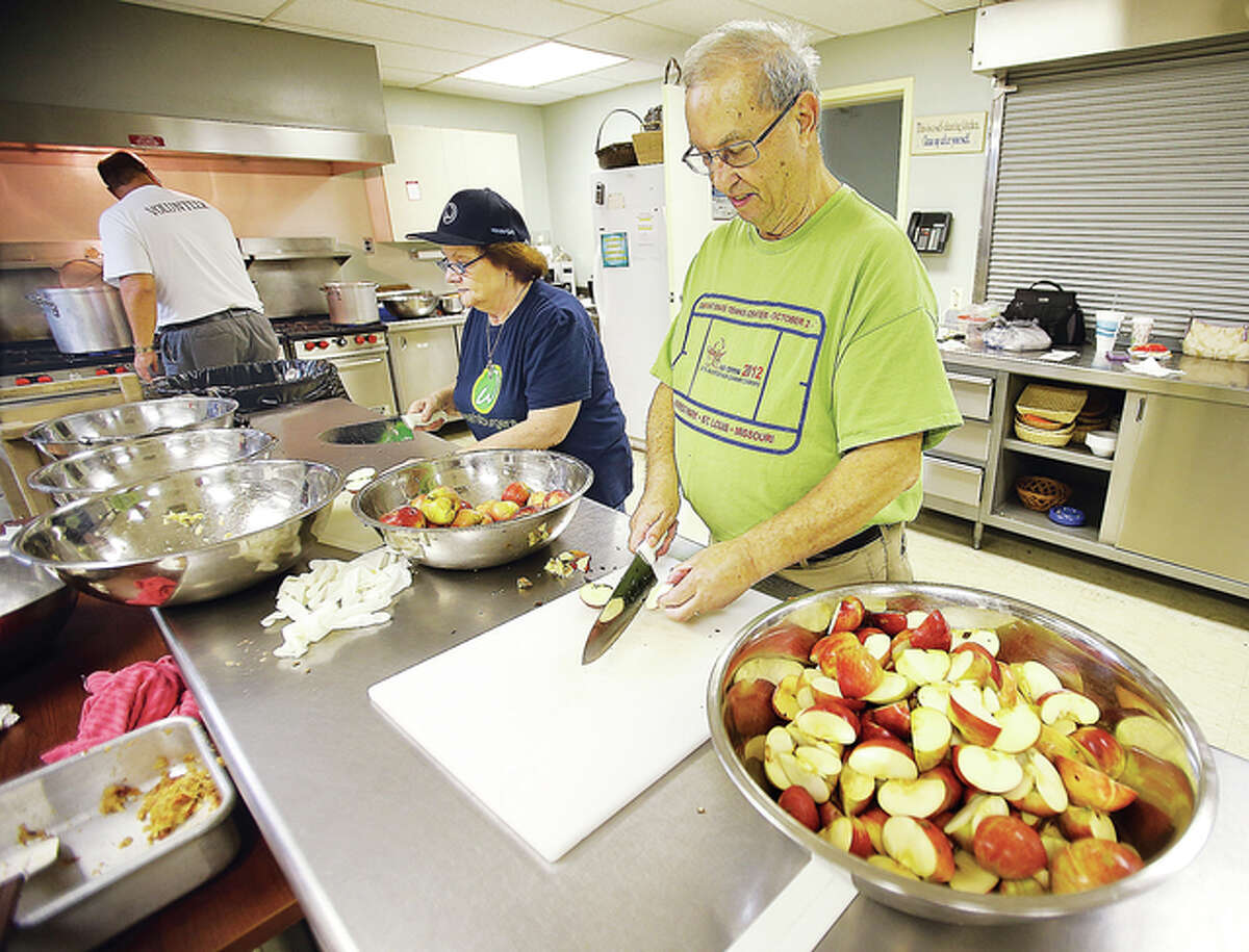 Judy Lageman, center, and Jerry Leonard, right, both of Godfrey, cut Jonathan apples from the Ringhausen Orchard Friday afternoon at the Main Street United Methodist Church in Alton.