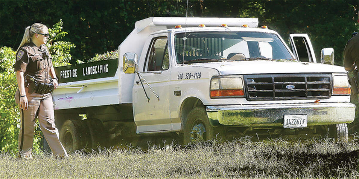 A Madison County deputy sheriff gets a look at the dump truck from Prestige Landscaping that ran over its driver Thursday on Reine Drive in Godfrey. Fire officials said the truck was sliding down an embankment when the driver tried to jump out and was pulled underneath the truck. He was transported to a St. Louis hospital from the scene by an ARCH Air Medical Services helicopter.