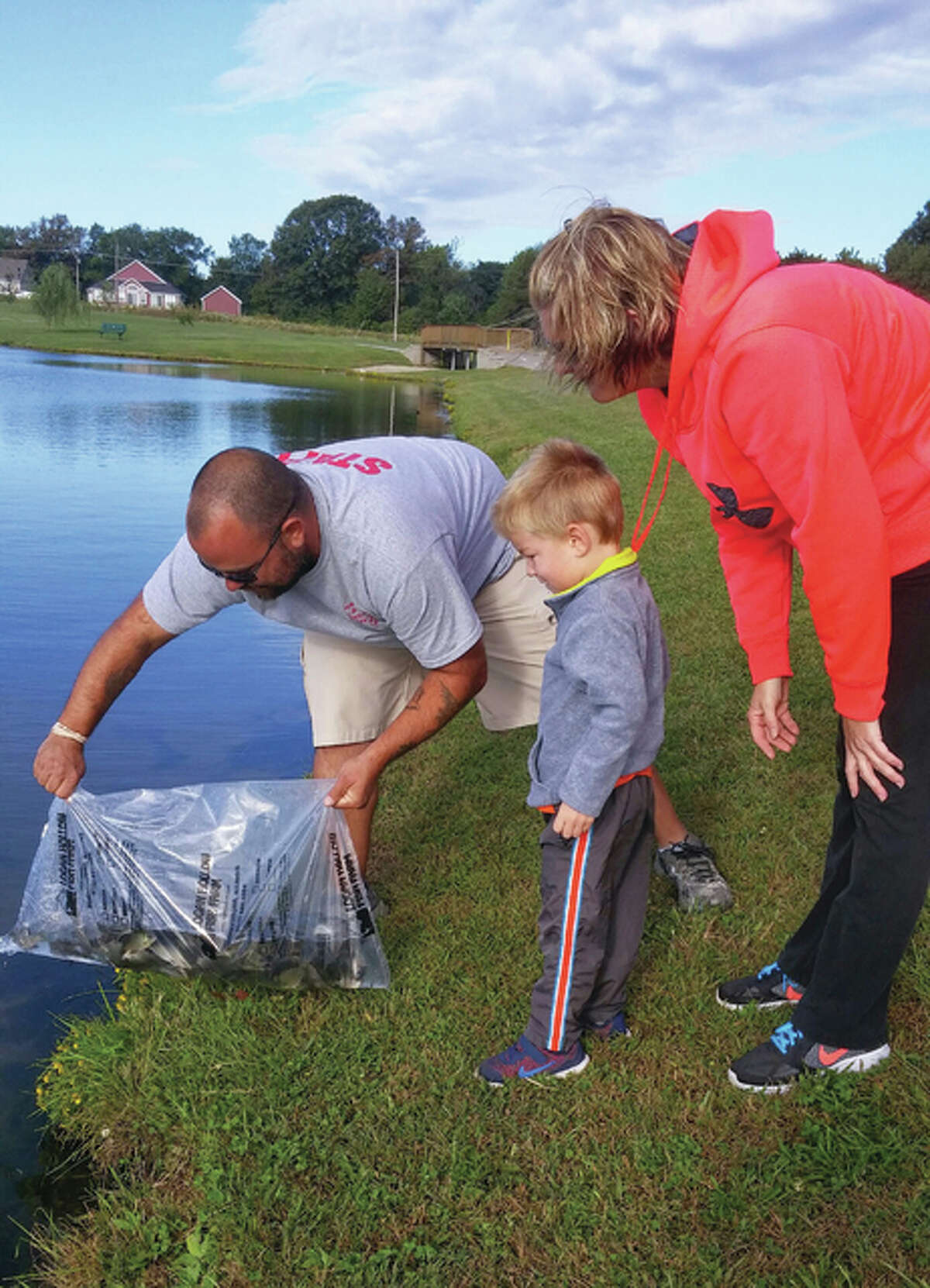 Carson Hutchens, 3 years old, of Jerseyville, watched in awe with his mother, Amy Hutchens, as John Stiles, JPRD Recreation Supervisor, release fish into the lake on Wednesday morning.