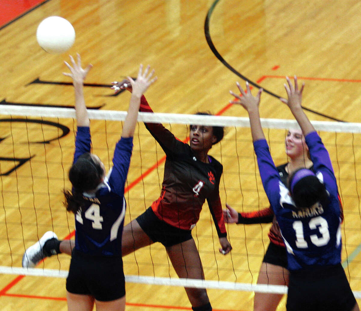 Edwardsville senior Sydney Wright (middle) sends the ball past the block of Collinsville’s Ellie McCarthy (left) and Ayona Tharps (13) in the Tigers’ SWC volleyball victory Thursday at Lucco-Jackson Gym in Edwardsville.