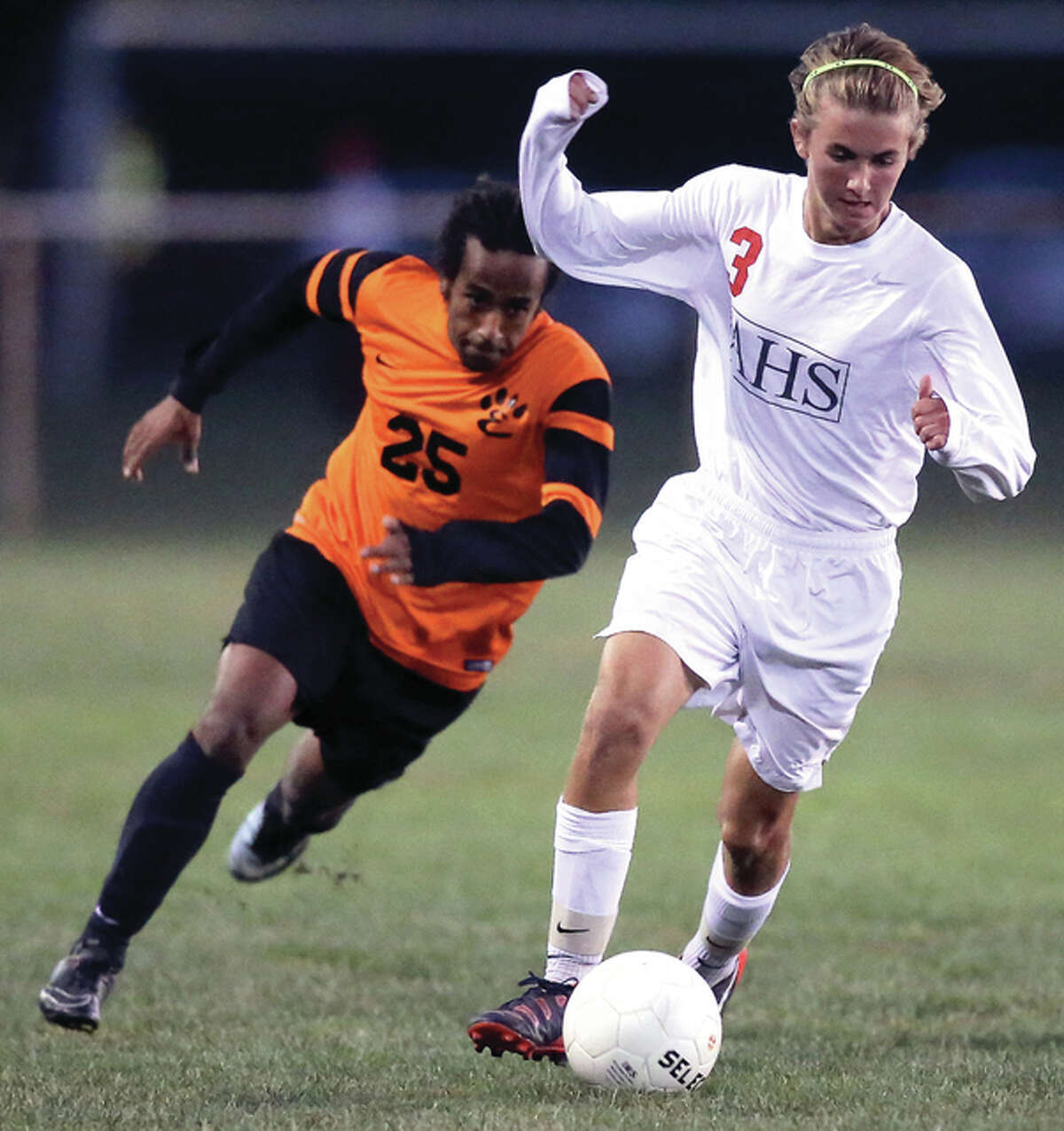 Edwardsville’s Hamada Freese (left) pursues the play while Alton’s Adam Kane (3) pushes the ball upfield during the Redbirds’ 1-0 SWC victory over the Tigers on Thursday night at Moore Park in Alton.