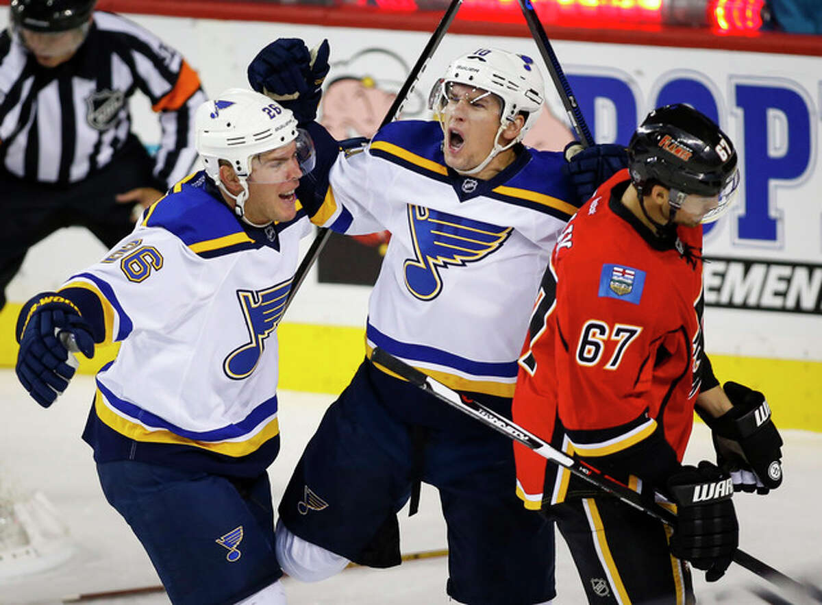 The Blues’ Scottie Upshall, center, celebrates his goal with teammate Paul Stastny, left, as Calgary Flames’ Michael Frolik, from the Czech Republic, skates by during the first period Tuesday in Calgary, Alberta.