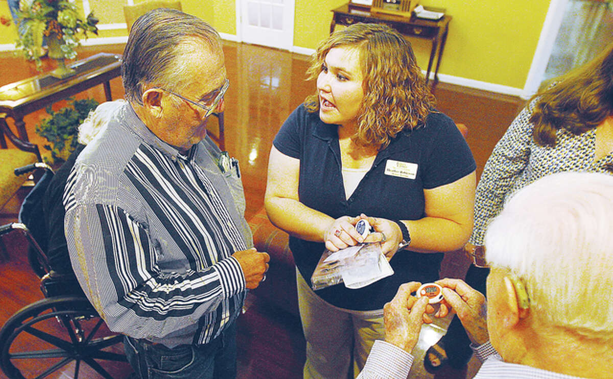 Foxes Grove activity assistant Heather Robinson, center, shows residents how to use a device intended to keep track of how many steps they take while walking each day.