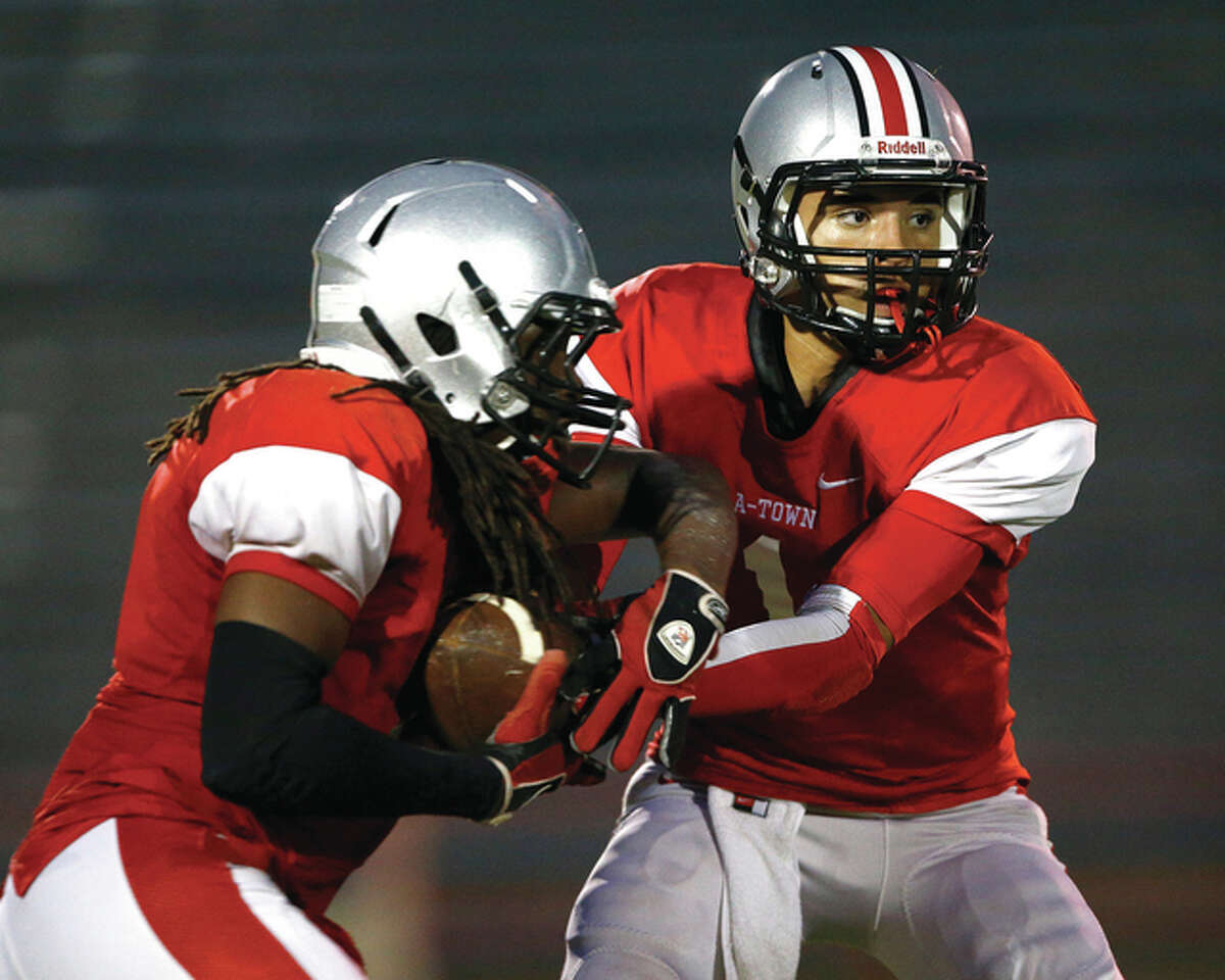 Alton QB Keenan Stegall (right) hands the ball off to Jameyon Alexander during their season opener against Rock Island at Public School Stadium in Alton. The 1-6 Redbirds are back in action Friday night at Edwardsville, where the unbeaten Tigers look to clinch at least a share of their third straight Southwestern Conference title.