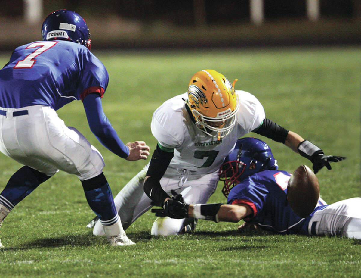 Southwestern’s Jesse Arnold (middle) scrambles to pull in a loose ball — he was ruled down on the play — after being tackled by Carlinville’s Jacob Dixon (right) early in the first half Friday night in Carlinville. Dixon had a big night offensively for the Cavs, rushing for 216 yards to push his season total to 1,562. Carlinville defeated the 3-5 Piasa Birds 28-0 to improve to 6-2 and clinch a playoff appearance for the 15th time in 16 years, including the last nine in a row. It was also victory No. 600 in the history of Carlinville football.