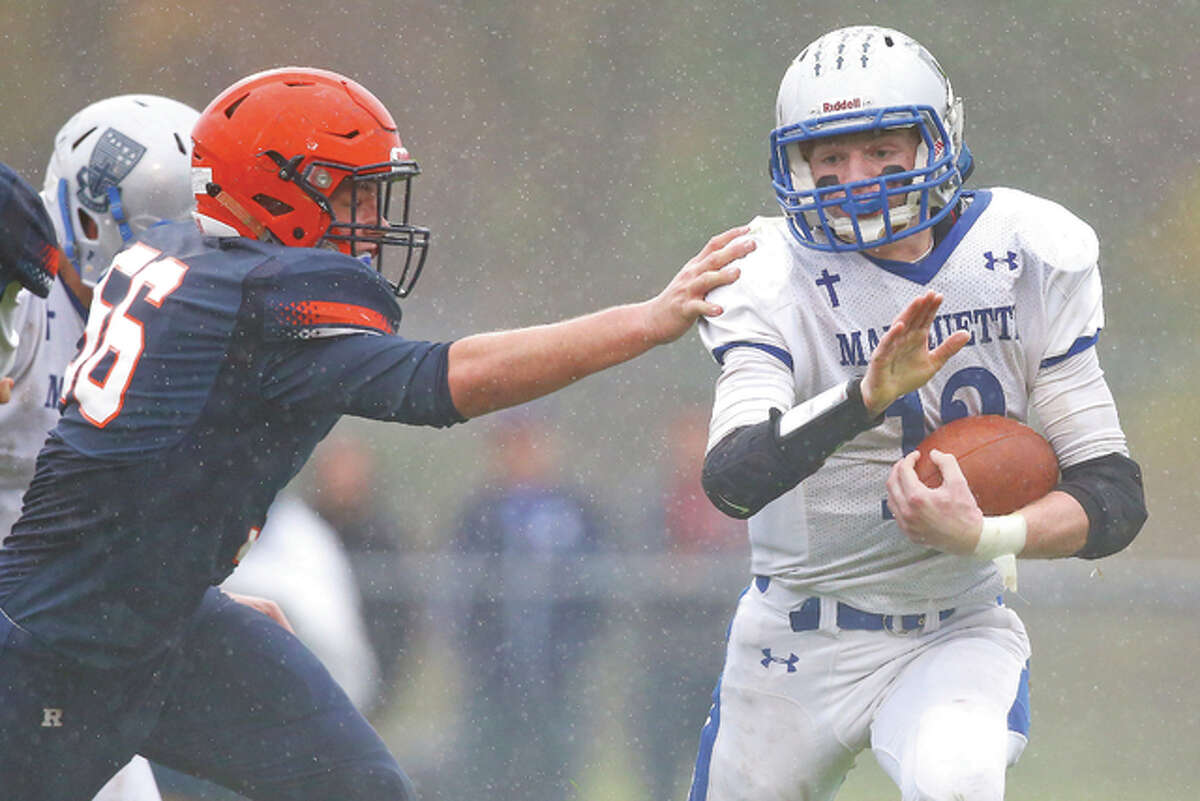 Marquette running back Brady McAfee escapes the grip of Rochester linebacker Austin Mathis in Saturday’s first-round Class 4A playoff game in Rochester. The Rockets won the game 52-7.