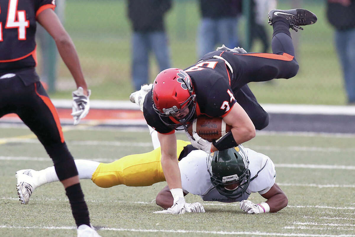 Edwardsville’s Jackson Morrissey (34) gets tripped up by Waubonsie’s Trevon Moore (14) in the first quarter of Saturday’s Class 8A playoff game in Edwardsville. The Tigers were upset by No. 30 seed Waubonsie, 20-17, ending their season.