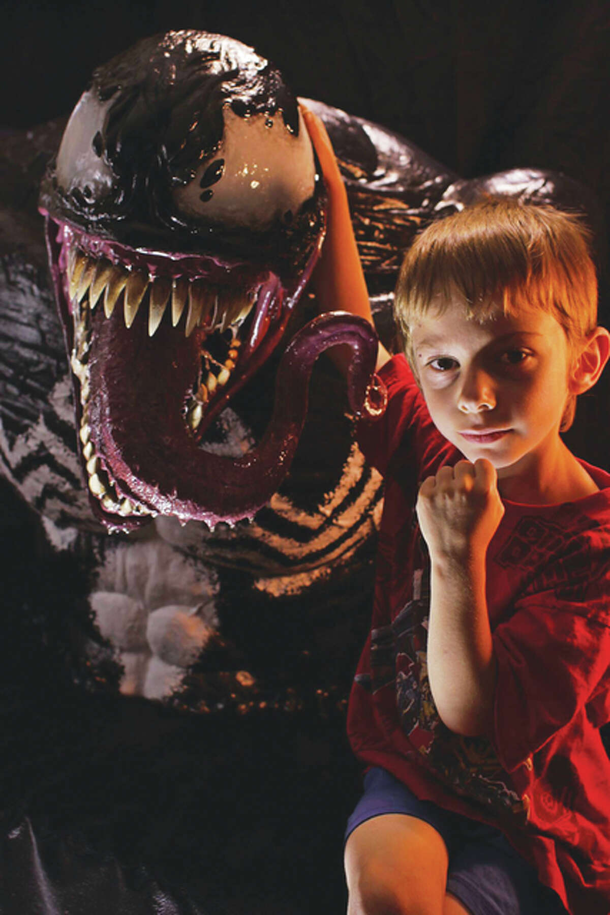 A life size sculpture of the super villain Venom with a human child for size comparison.
