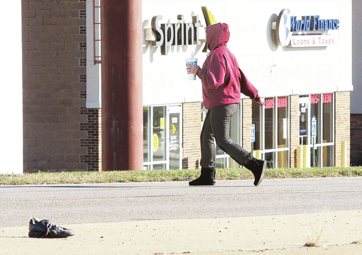 A woman Monday morning runs across the 1700 block of Homer Adams Parkway in Alton near the spot where a 24-year-old East St. Louis man was killed crossing the same highway just before 6 p.m. Sunday evening. A shoe, which may or may not be related to the death, is in the median.
