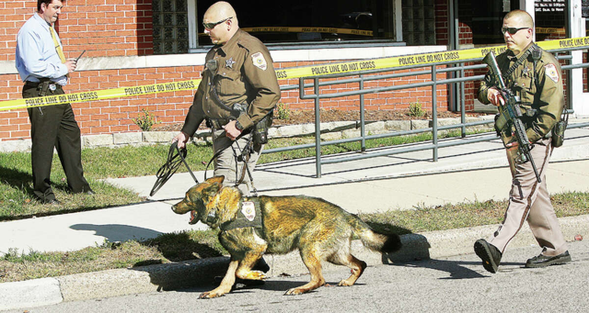 Heavily armed Madison County Sheriff’s deputies start a track with a canine Tuesday from the Vantage Credit Union, 217 E. Ferguson Ave. in downtown Wood River, after two men reportedly armed with handguns robbed the establishment. Police from the sheriff’s department, Roxana, Hartford, South Roxana, East Alton and Wood River searched the neighborhoods and set up a perimeter for the two men, but they apparently eluded capture.