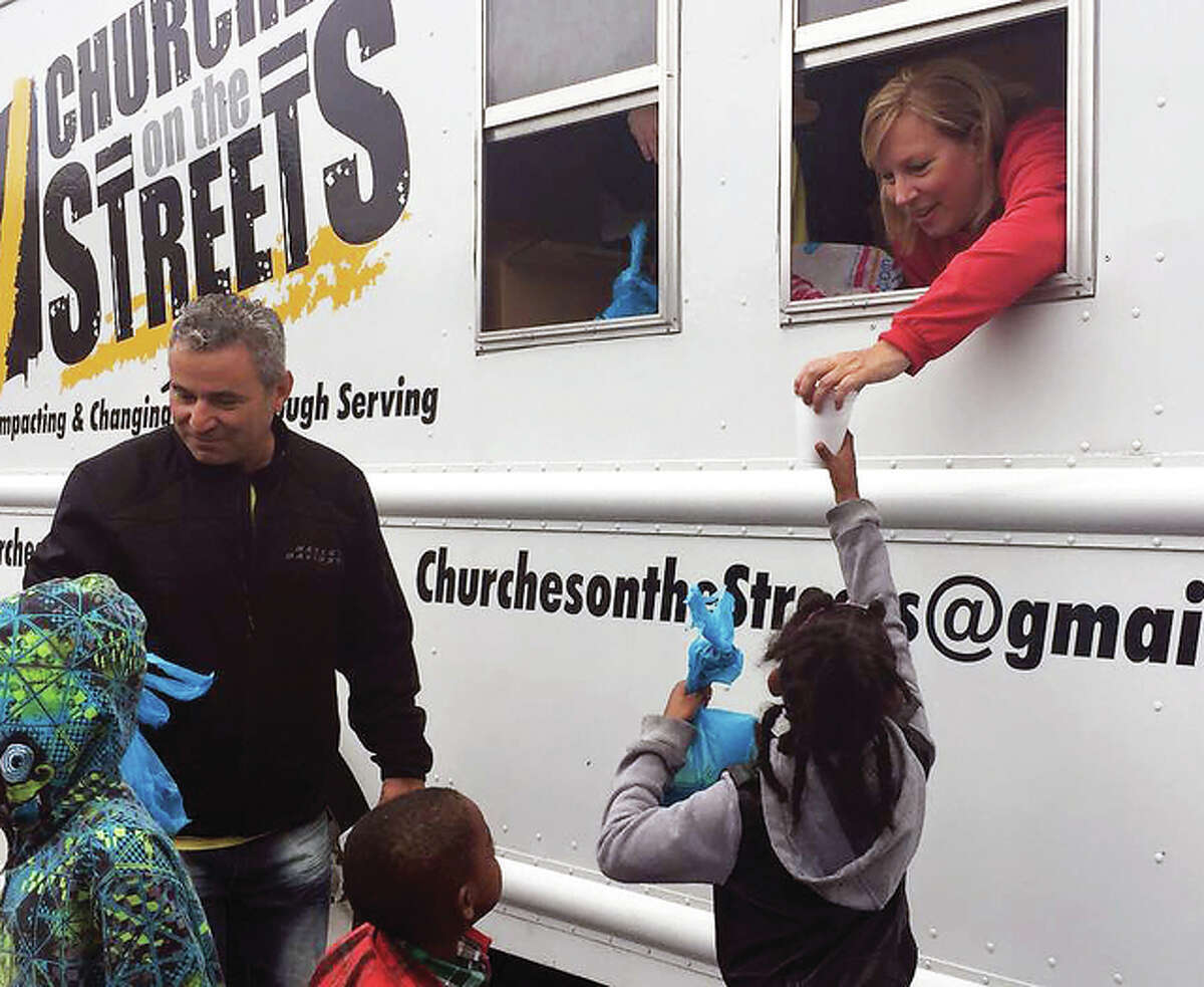 Ralph Valdes and his wife Angela Valdes, founders of Churches on the Streets, a Christian organization, provide food and clothing to children from their truck during an event earlier this year.
