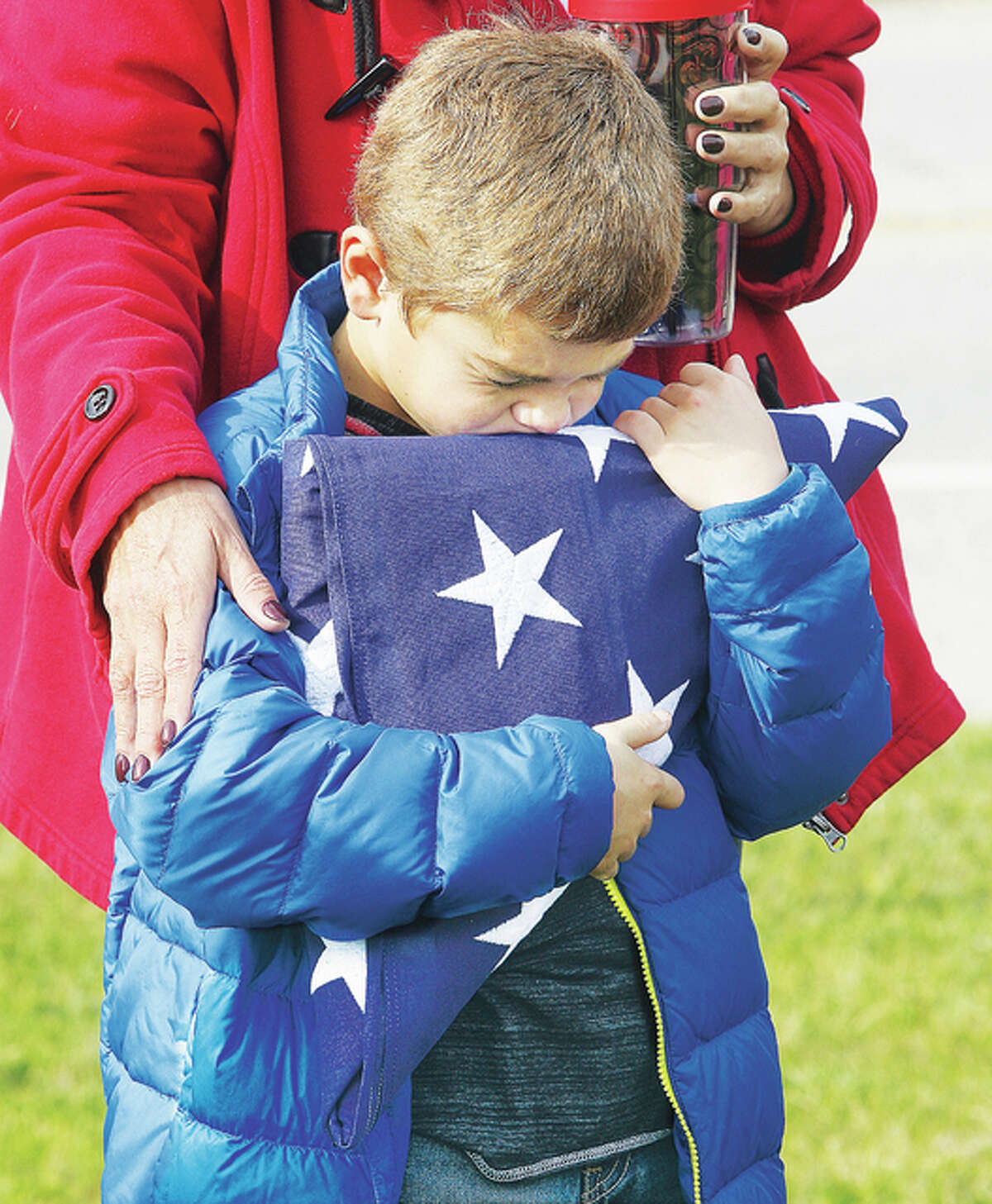 Reid Murray, 8, clutches the folded flag that was his grandfather’s during the annual Veterans Day ceremony in front of the Doughboy Statue at the Alton VFW Post 1308 Wednesday. Murray’s grandfather, Thomas E. Hooper of Alton, was a Vietnam War veteran who passed away in September. A crowd of about 50 attended the annual ceremony.