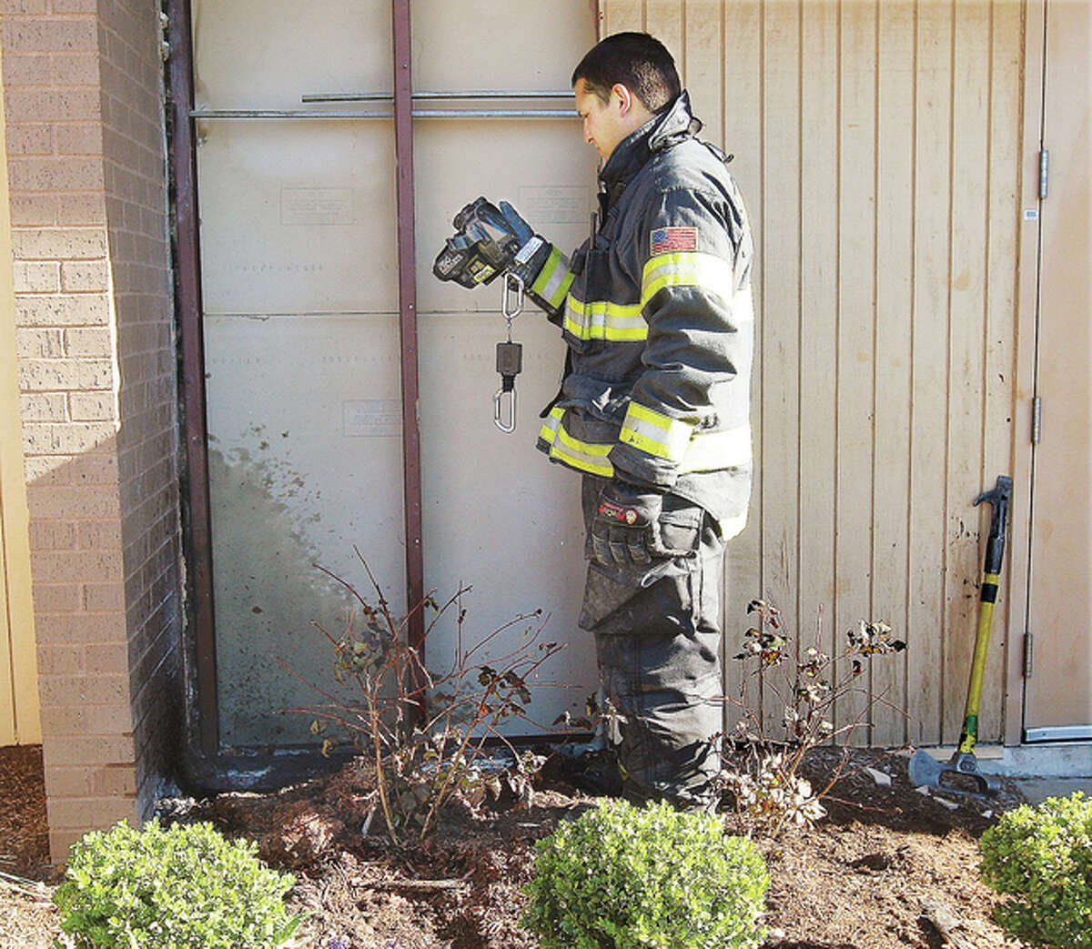 An Alton firefighter uses a thermal imaging camera to check for any hot spots in the wall near the upper level south entrance to Alton Square Thursday after a fire in the mulch traveled up the wall and filled Olga’s Restaurant with smoke, forcing an evacuation of the entire mall. Firefighters tore siding and insulation off the wall to exposure the fire.