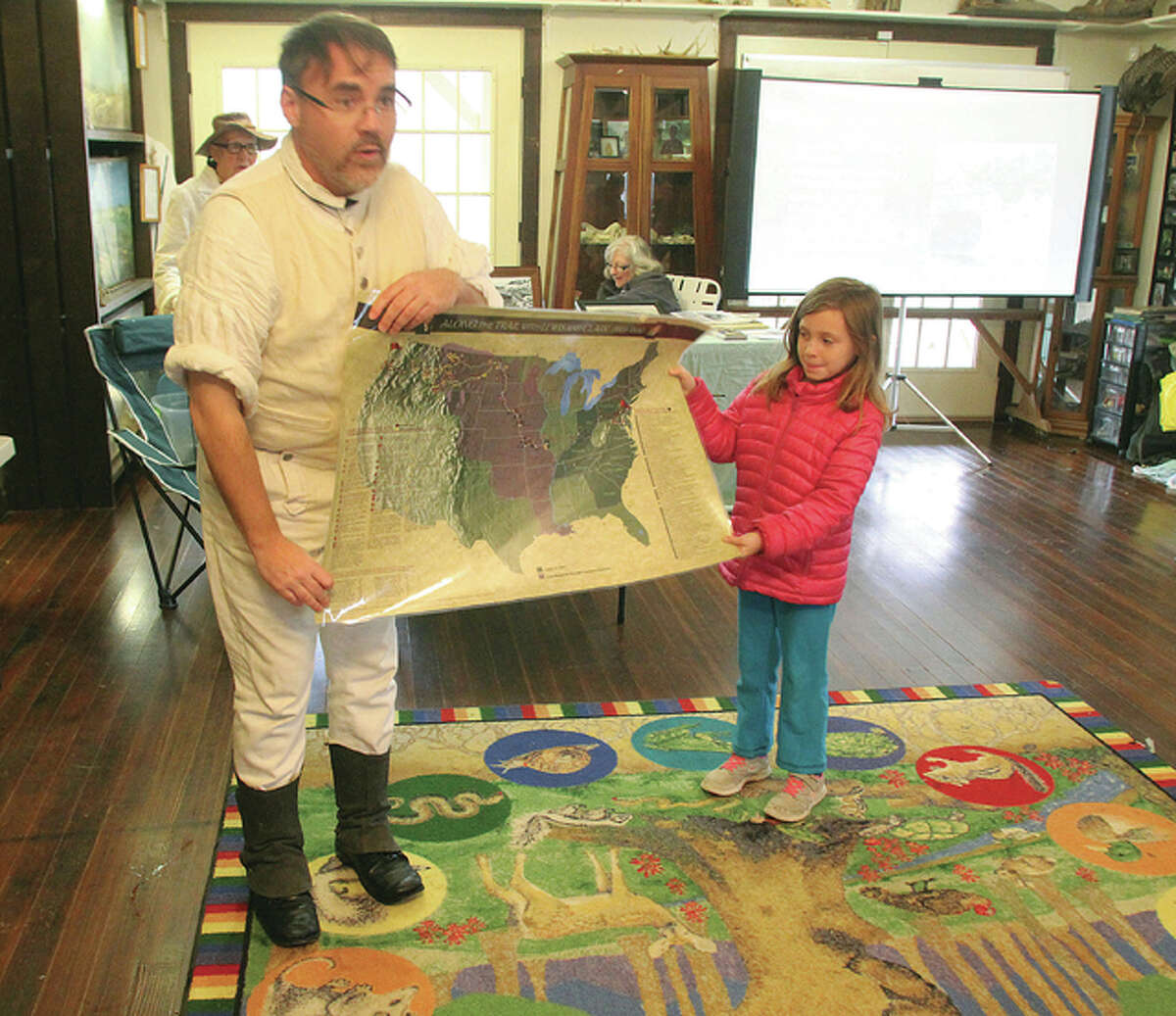 Brad Winn, site manager at the Lewis and Clark State Historic Site, uses a map with the help of Samantha Hall, 6, to talk about the Lewis and Clark Expedition during “Living History: A Walk Through Time” Saturday at The Nature Institute in Godfrey.