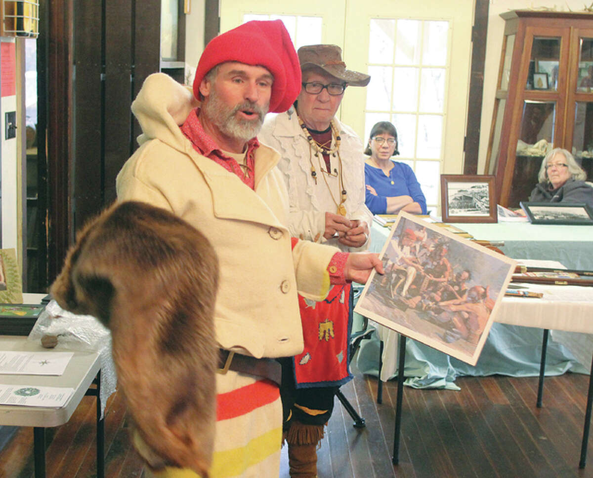 Steve Bollini, left, as a French fur trapper, talks about the fur trade while John Langley of the Alton Museum of Art and History waits for his turn during “Living History: A Walk Through Time” Saturday at The Nature Institute in Godfrey. Because of bad weather the hiking portion of the program was cancelled, but presenters gave talks on a variety of subjects indoors.