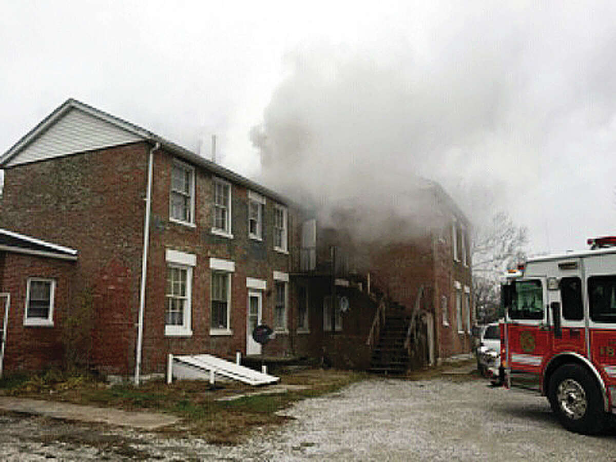Smoke billows from an apartment building on Mills Avenue Saturday morning. Fire seriously damaged the brick house, built in the 1850s, that now serves as a 10-unit complex.