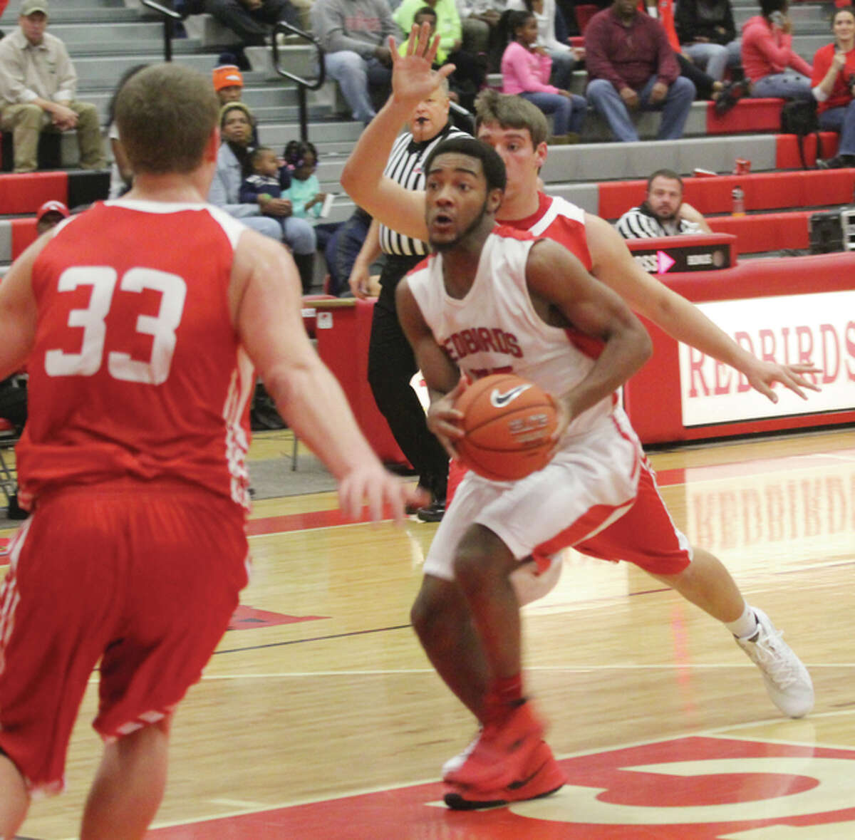 Alton’s Marcus Latham looks to the basket after getting past Jacksonville’s Joe Brannan while the Crimsons’ Tyler Rose (33) closes in on the play Saturday night at Alton High in Godfrey.
