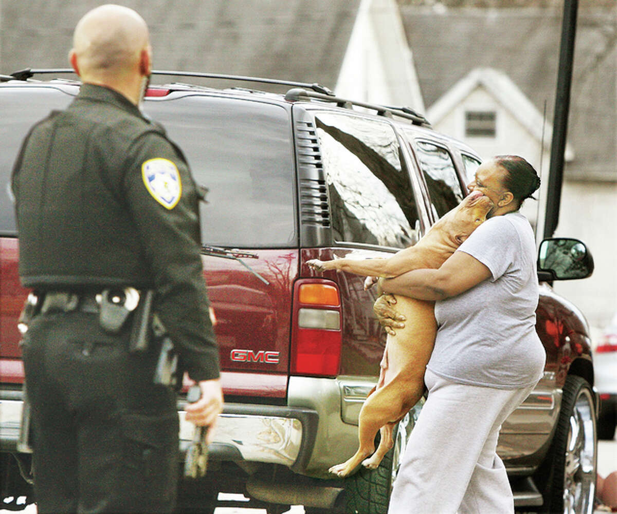 A woman retrieves her female pit bull Wednesday from a yard at the corner of Highland and Elliott Avenues in Alton after police surrounded the animal, guns drawn, because it allegedly acted aggressively toward students getting off a school bus nearby. The school bus apparently reported that some students had to jump onto a car to avoid the dog. Four officers, including Chief Jason “Jake” Simmons responded to the call and surrounded the dog until the owner, who apparently lived elsewhere, came to get the dog. The dog appeared to have recently had puppies. No children were injured.