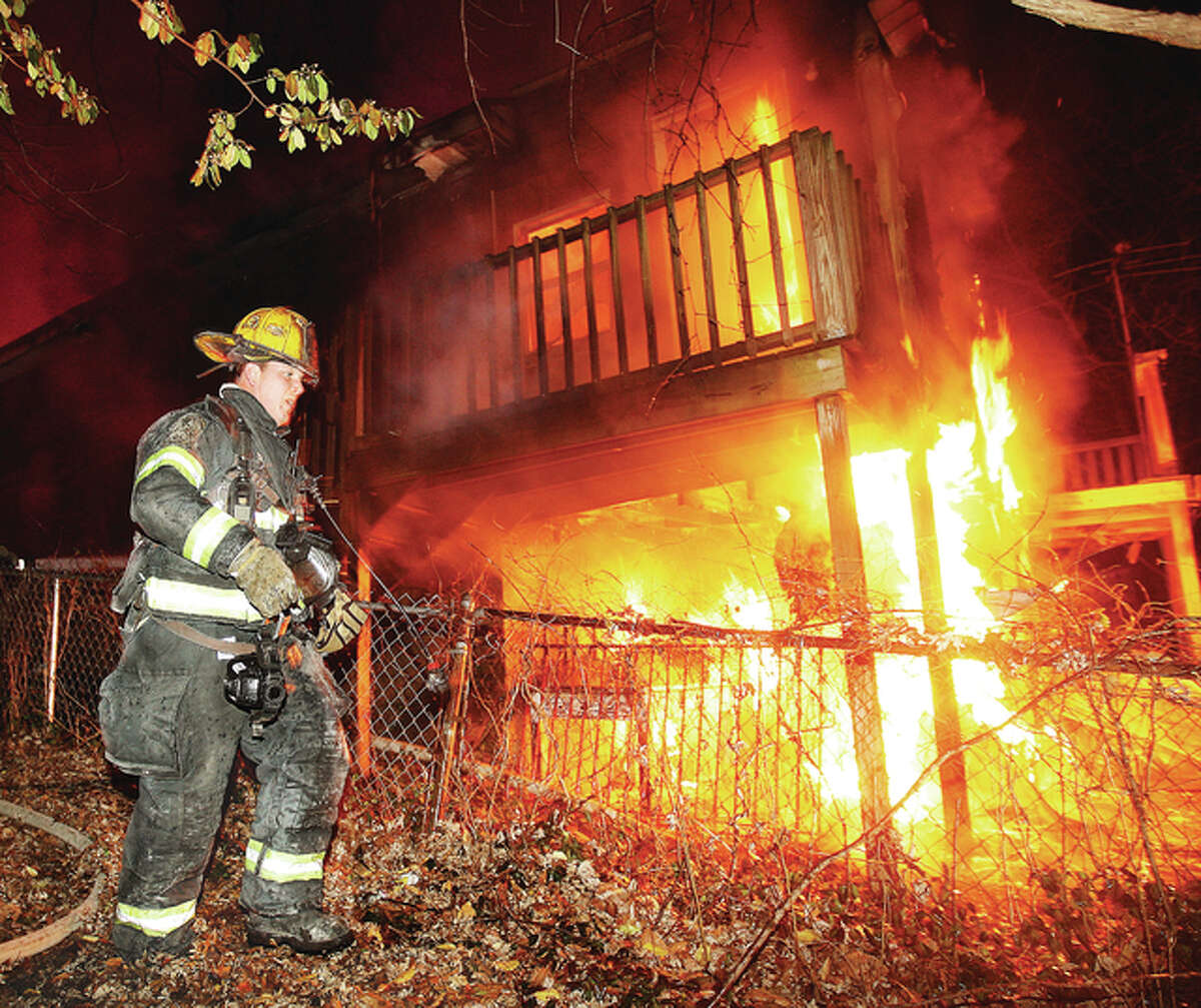 Alton Fire Department Engineer Thomas Davison moves to the fully-engulfed rear of 2105 Locust St. in Alton late Thursday night as fire guts the vacant house which was reportedly in the process of being restored. Alton firefighters called East Alton firefighters to the scene for assistance. Nobody was injured in the blaze which fire officials said was the seventh house fire in the city in two months.