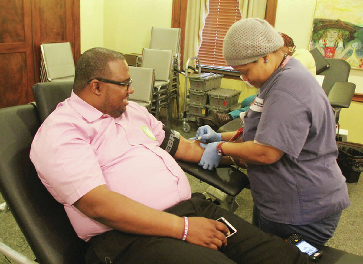 Steed Cross, of Alton, gives blood with the help of Red Cross collection specialist Shalvona Dickens, during the A Precious Organization Holiday Sickle Cellebration, a combination blood and toy drive, held Saturday at the YWCA of Alton.
