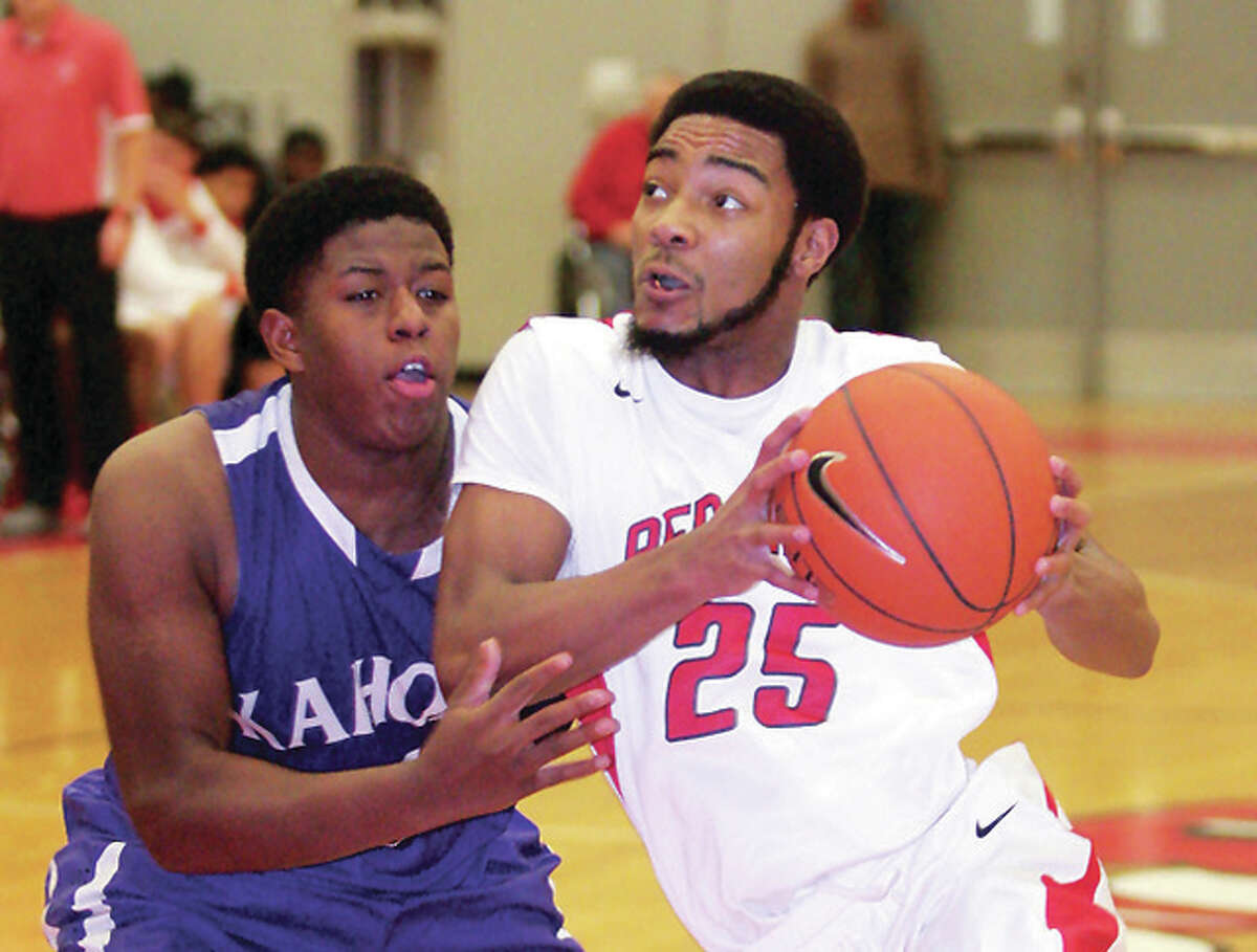Alton’s Maurice Edwards drives past Collinsville’s Laron Johnson for a basket in Friday night’s SWC game in Alton.