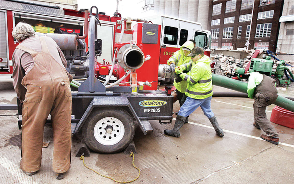 After one of the city of Alton’s largest pumps began to have difficulties, the city called on the resources of the Phillips 66 operated refinery in Roxana for a large pump. City workers hook hoses to the pump Wednesday after it was delivered by refinery firefighters to the foot of State Street.