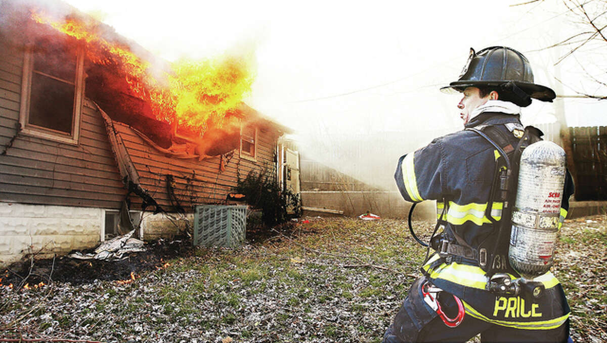 Alton firefighter Wayne Price stands by for his hose line to be charged Tuesday at the rear of a house in the 2800 block of Residence Street in Alton. Other firefighters were trying to navigate through the house to the source of the fire but Price brought the heaviest fire under control from the outside of the home. Alton activated a box alarm bringing East Alton firefighters to the scene to assist. The fire was contained to the rear of the home but the entire structure suffered smoke and water damage.