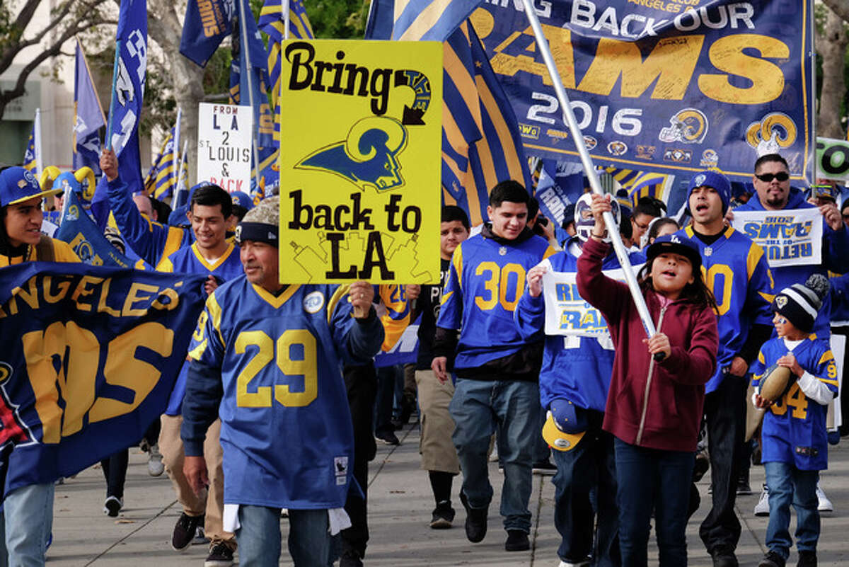Rams football fans hold banners, wave signs and chant while marching around the historic Los Angeles Memorial Coliseum. Saturday. Boisterous Los Angeles Rams fans gathered Saturday to herald the NFL team’s possible return after a 21-year sojourn in St. Louis.