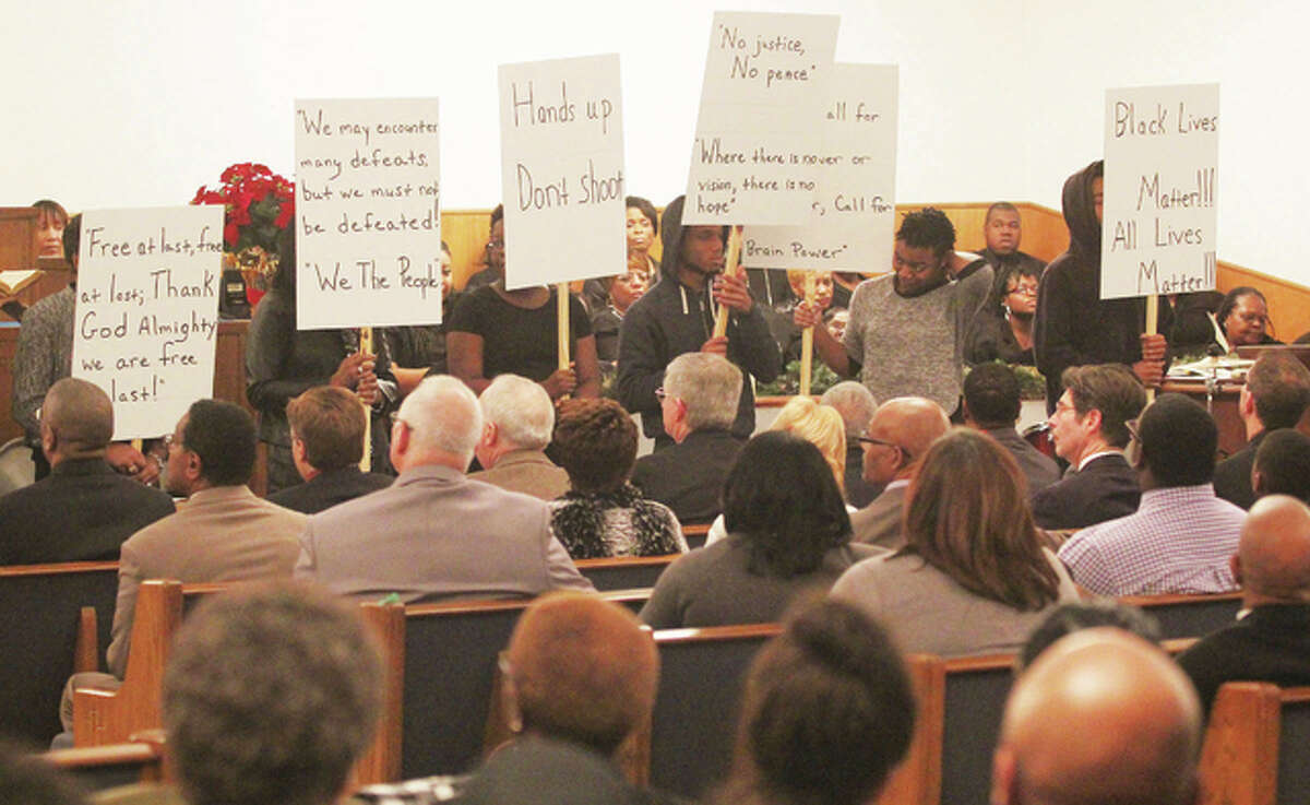 Participants hold signs reflecting the protest groups of the 1950s and 1960s compared to today in a skit, “Whose Protest is Best?,” during the Alton branch of the NAACP’s 36th annual commemoration of the Rev. Dr. Martin Luther King Jr. Sunday event at Tabernacle Missionary Baptist Church.