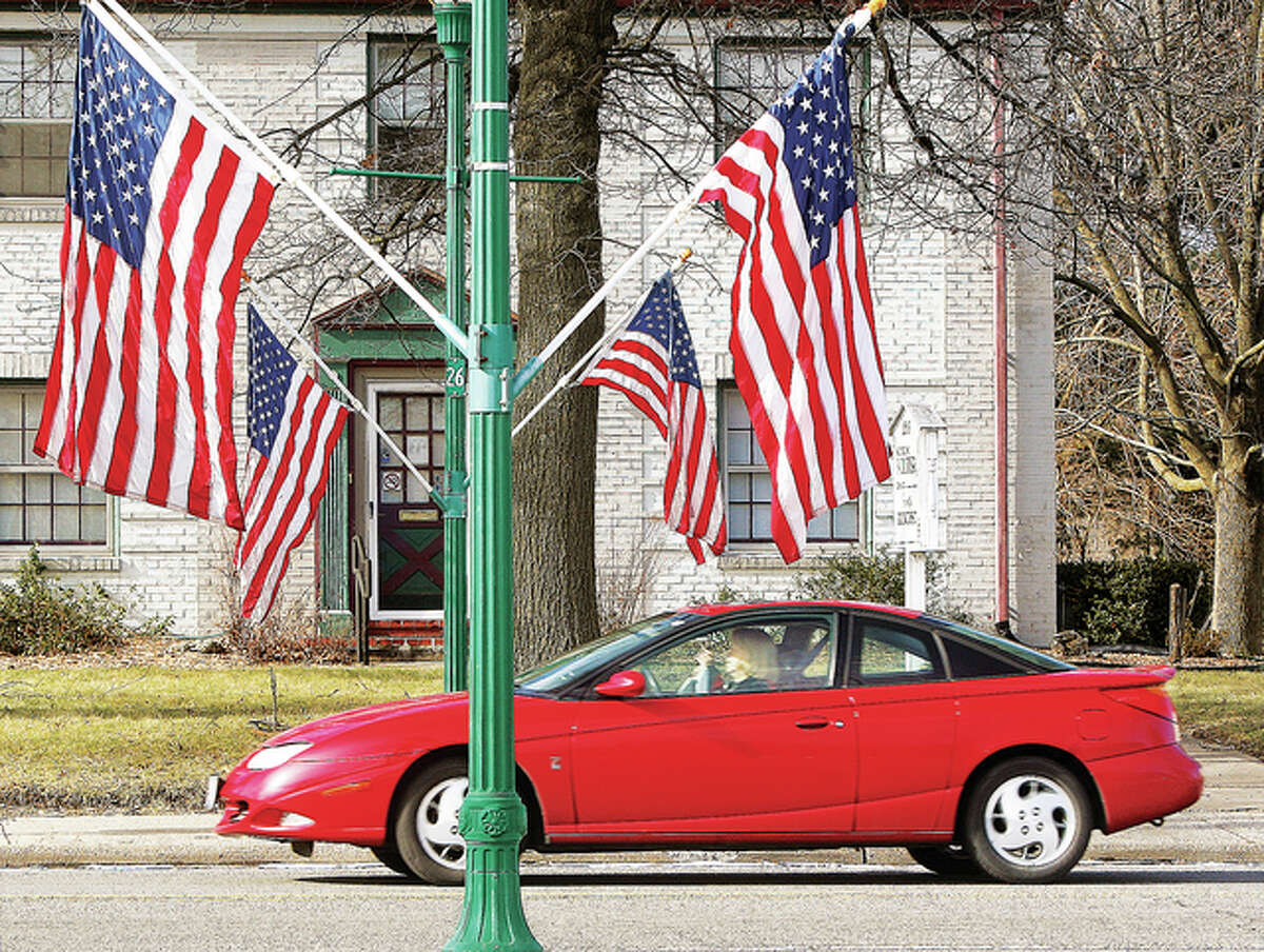 A red car passes along Washington Avenue in Upper Alton Monday past the dozens of flags set out to honor the slain civil rights leader.