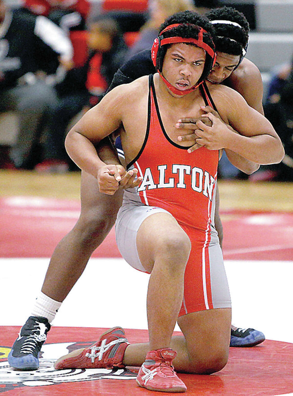 Alequan Russell of Alton, front, struggles to get free of East’s Duane Hill in the 220-pound bout Wednesday at AHS. Hill defeated Russell 3-1.