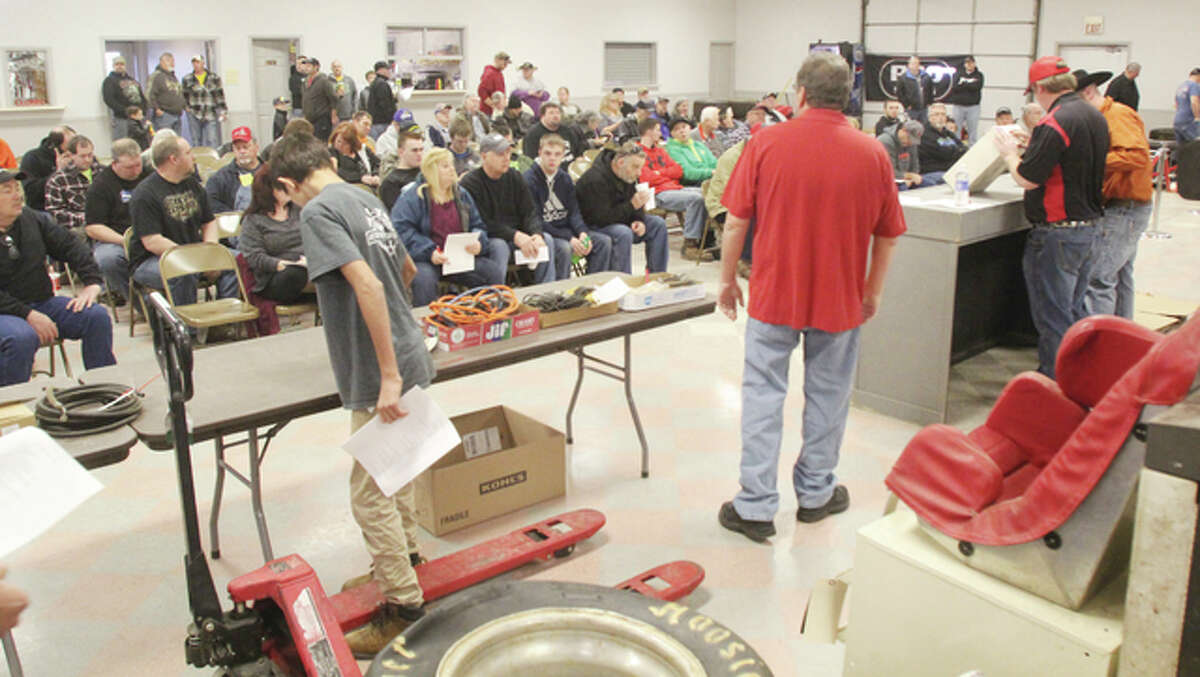 Workers move items up for bid at a racer’s auction Saturday at Hilltop Auction.