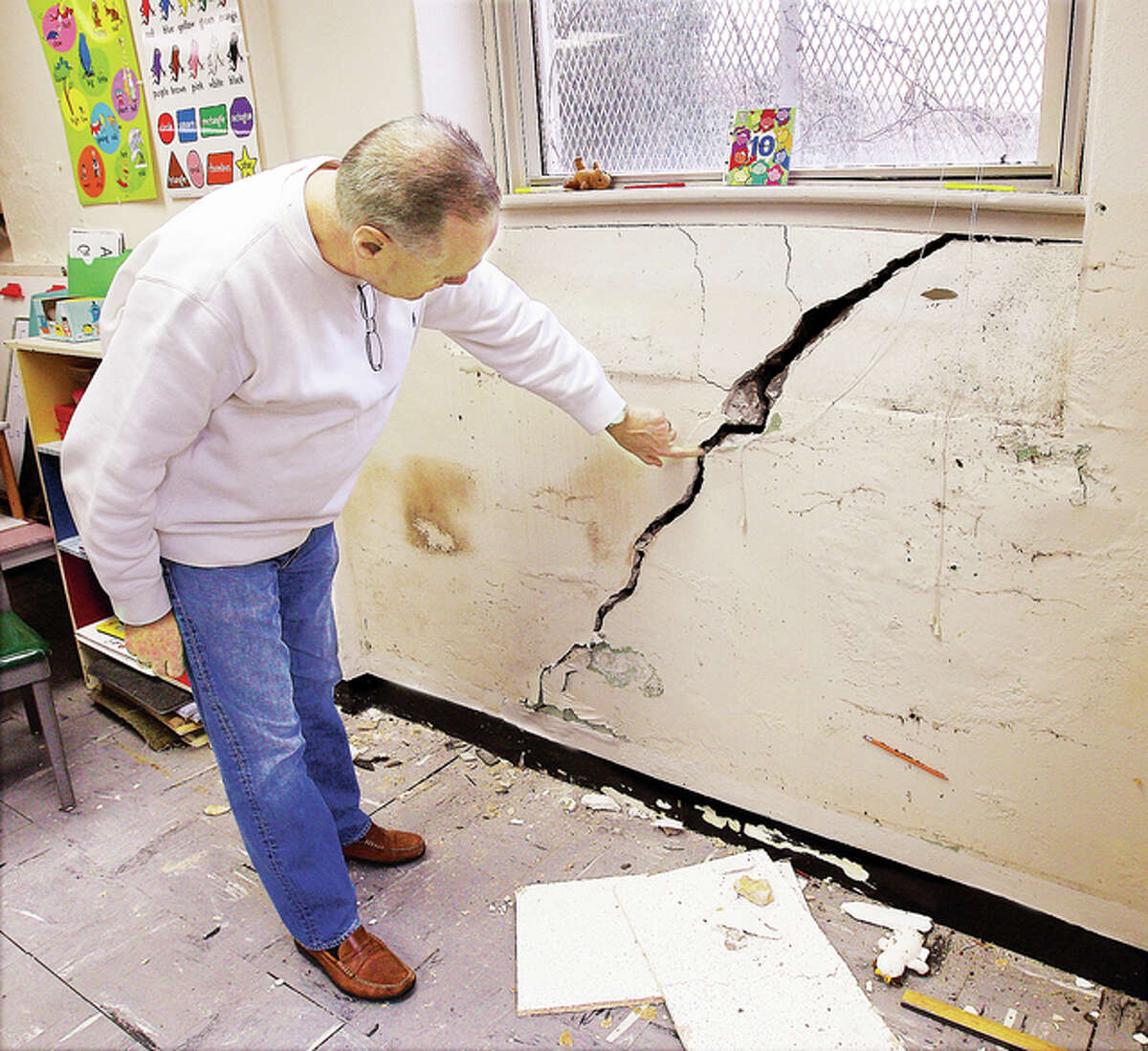 Ss Peter & Paul School principal Harry Cavanaugh in December examines a giant crack in the basement wall of the State Street school building. The school is settled in at the Mark Twain School on Milton Road, but Cavanaugh said they expect to be back in the old building for the next school year.