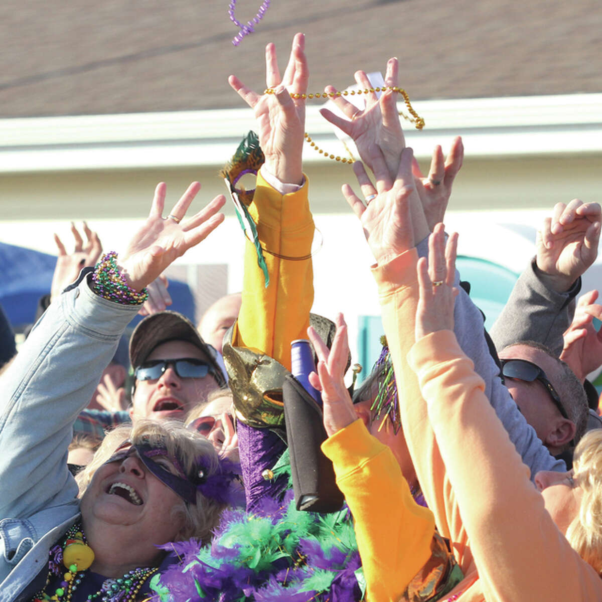 A group of spectators grab for beads thrown into the crowd during Wordi Gras, a “redneck Mardi Gras” held annually in Worden. Several hundred participants and several thousand spectators came out Saturday for the parade.