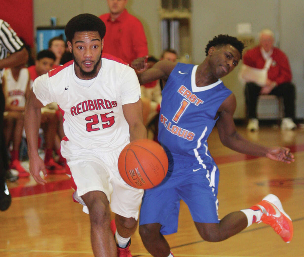 Alton’s Maurice Edwards(left) pushes past East St. Louis’ Kerion Chairs, who looks to avoid the foul as Edwards races upcourt on a Redbirds’ fast break Friday night at Alton High in Godfrey. Edwards scored 26 points in Alton’s Southwestern Conference victory.