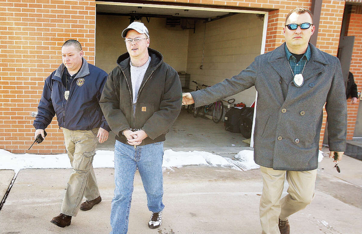 In this photo from last March, Bethalto Police Detectives Jeff Cope and Jason Lamb escort Liberty Bank Assistant Vice President Matt Liebheit, center, in handcuffs from the Bethalto police station to a car for transport to the Alton Police Station, a federal holding facility, after he was arrested for allegedly participating in a reported robbery of the Bethalto Liberty Bank branch at 333 W. Bethalto Drive on Dec. 13, 2014.