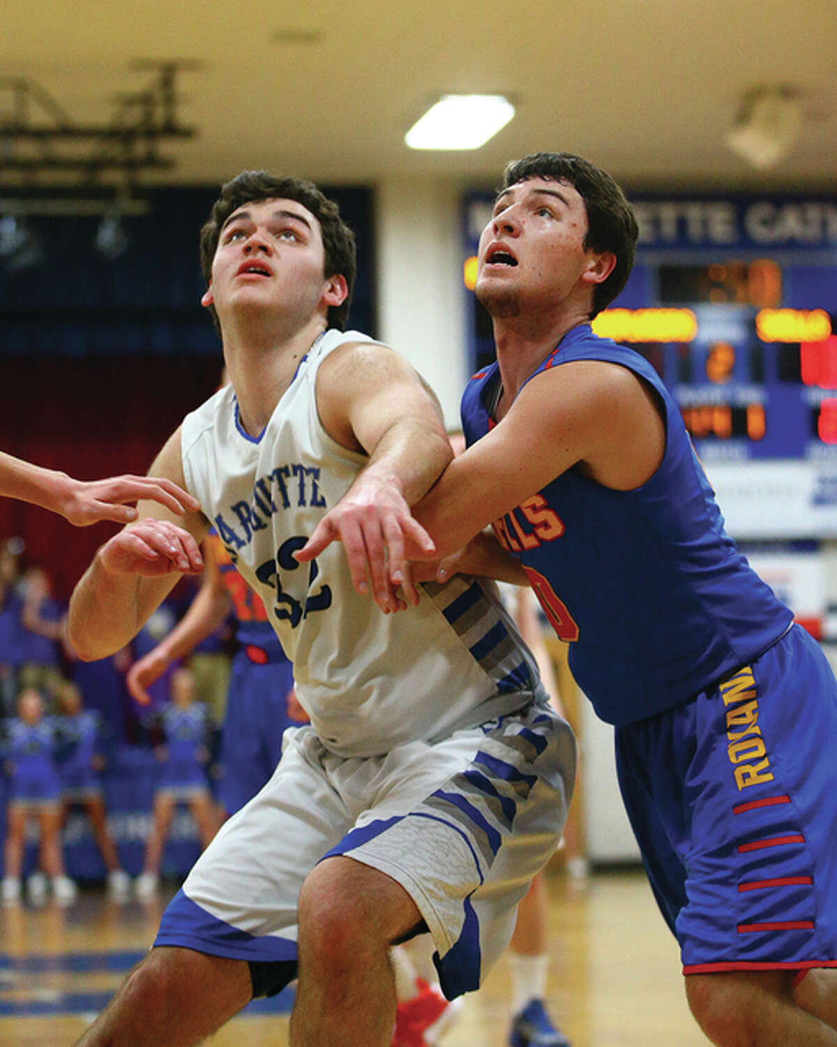Marquette Catholic’s Ben Sebacher (left) and Roxana’s Trace Gentry battle for position for a rebound during the first half Friday night in Alton.