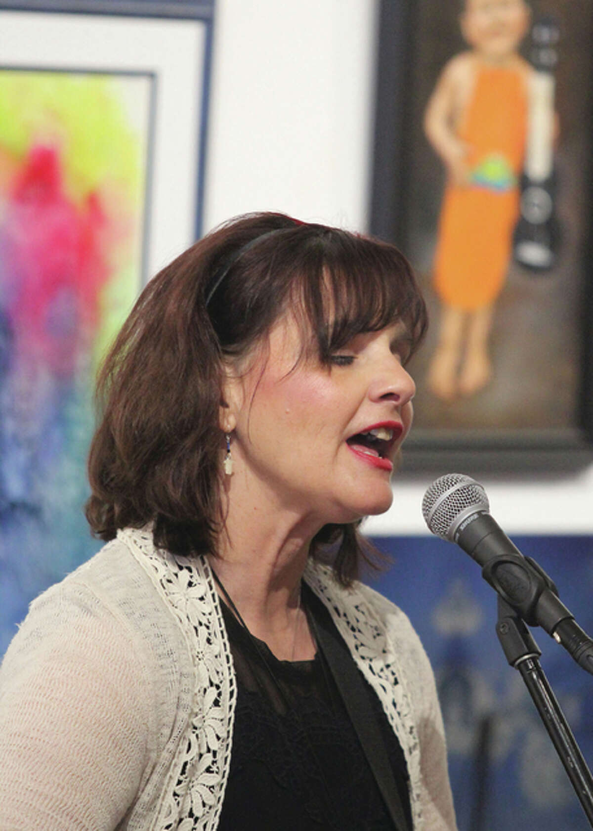 Framed by paintings from a recent juried art exhibit, Canadian-based singer Tia McGraff performs during a Valentine’s Day concert at the Jacoby Arts Center Sunday afternoon in Alton, where her husband and musical partner, Tommy Parham, has roots.