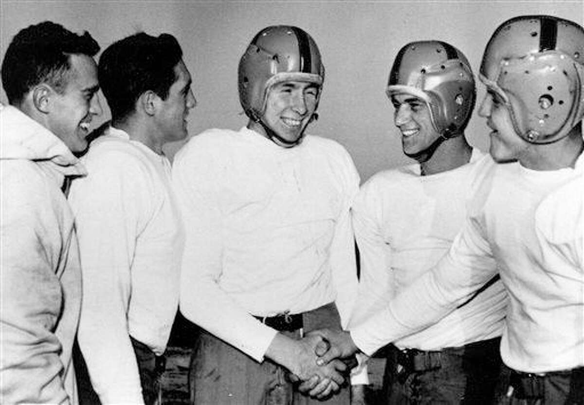 In this Dec. 11, 1953, file photo, Notre Dame player John Lattner, center, winner of the 1953 Heisman tropy and second-time winner of the Maxwell trophy, receives congratulations from teammates at practice in South Bend, Indiana.