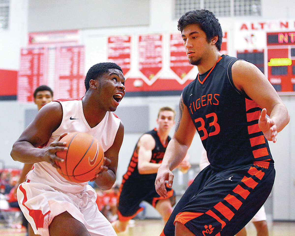 Alton’s Paul Harris, left, drives to the basket against Edwardsville’s AJ Epenesa in Friday night’s Southwestern Conference basketball game at Alton. Both players scored 20 points in the game.