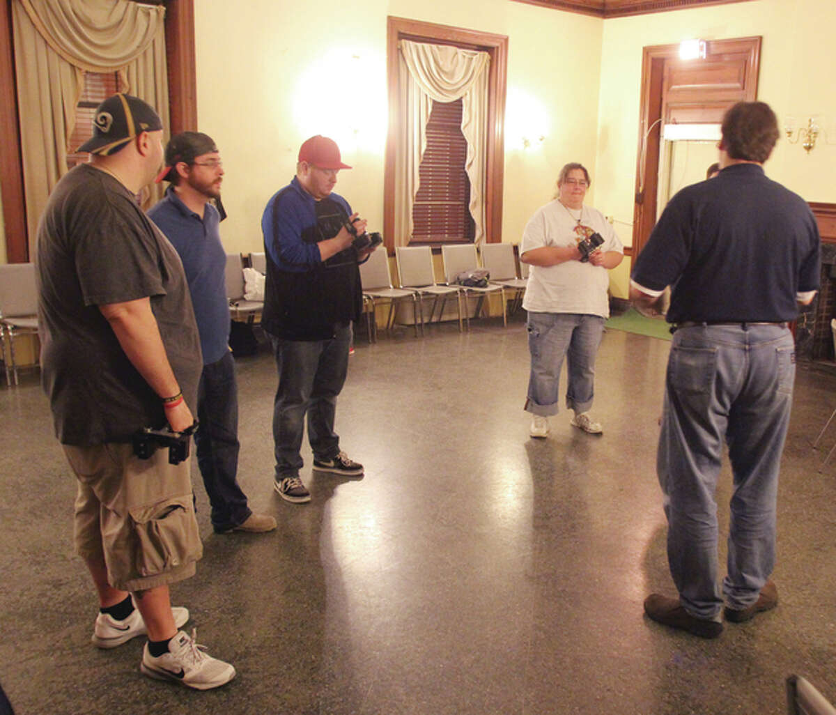 Mark Farley, far right, founder and owner of the St. Louis Paranormal Research Society, shows participants how to use equipment during a haunted tour of the Alton YWCA. Alton has a reputation for hauntings, and Farley said the YWCA is one of the more active spots.