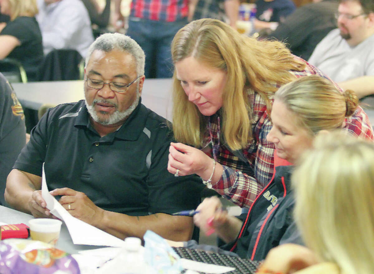 All Martinez, Corinne Harris and Sam Martinez try to identify 1980s cartoons by looking at pictures of the characters during a trivia night fundraiser for the South Roxana Fire Department Saturday at the Wood River VFW.