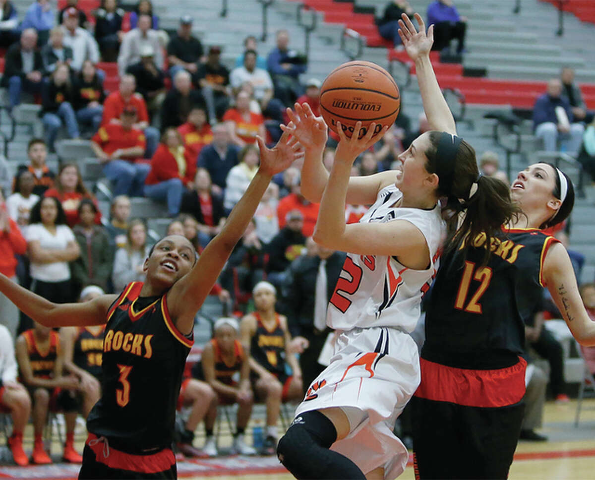 Edwardsville’s Makenzie Silvey drives and shoots while defended by Rock Island’s T’Nauzhae Robinson (left) and Mariah Hoover (right) during the championship game of the Alton Class 4A Sectional at Alton High. Silvey scored 21 points in the Tigers’ 59-42 victory. Edwardsville led 17-0 in the first quarter before the Rocks rallied to tie 42-42. The Tigers then responded with a 17-0 run to close the game. Edwardsville, ranked No. 3 in the final Class 4A state poll, improves to 30-1 and advances to play Lisle Benet Academy (29-3) in the Bloomington Super-Sectional at Illinois Wesleyan’s Shirk Center at 7 p.m. Monday. The 30-win season is the ninth in the last 10 years for Edwardsville, which has won nine sectional championships in that span. Rock Island, ranked No. 7 in the state while setting a school-record for victories in a season, closes at 29-4. The Rocks, who last won a sectional in 1991, were also eliminated by the Tigers in the sectional title game last season, falling 53-51 at Pekin.