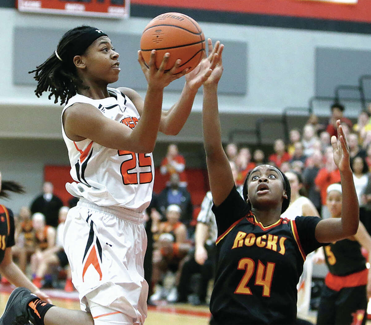 Edwardsville junior Criste’on Waters (left) puts up a shot over Rock Island’s Markyia Williams-Miles during the second half of the Tigers’ win in the Alton Class 4A Sectional championship game Thursday night at Alton High in Godfrey.