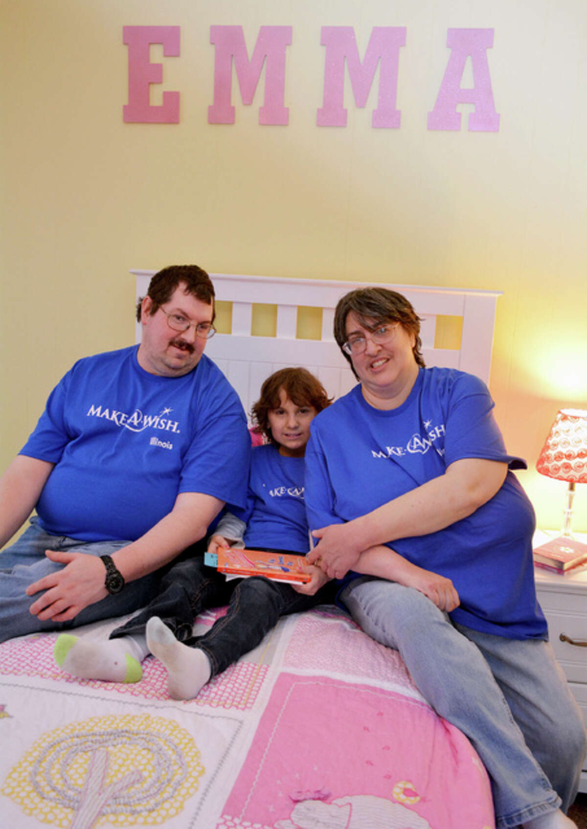 In this Jan. 14, 2016 photo, 8-year-old Emma Kocher, who has been fighting cancer, is flanked by her parents Brent and Amy on her new bed at their home in Sainte Marie, Ill. After years of sharing a bedroom with older sister Bailey, her parents gave up their master bedroom and volunteers converted the garage into a new master bedroom for Emma.