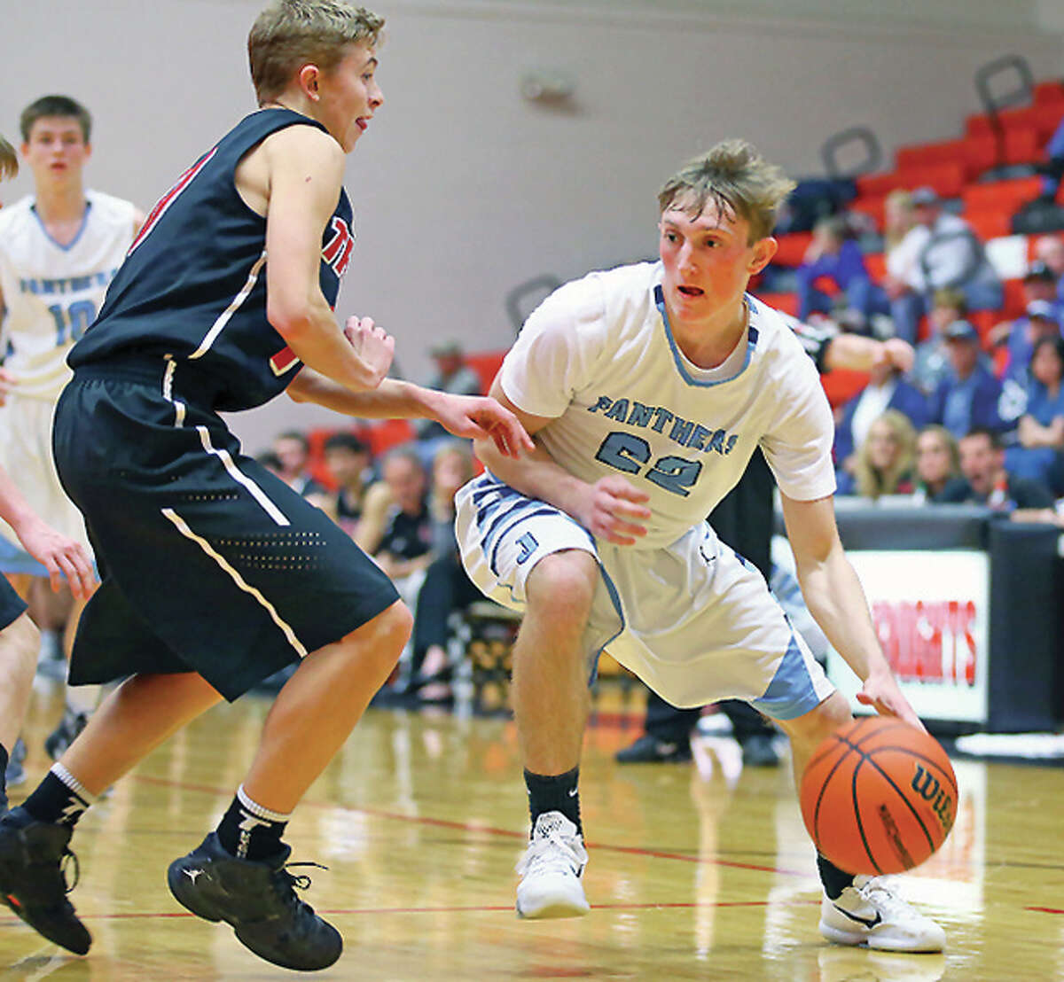 Jersey’s Zac Ridenhour, right, drives the lane against Triad’s Brendan Grigg in Monday night’s Class 3A Regional quarterfinal game at Triad High School. Jersey won the game 65-41.