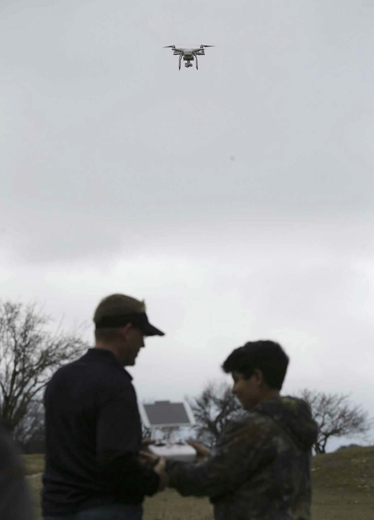 San Antonio Drones' Chris Fisher (left) shows Zeus Blowe, 11, how to fly a drone as hobbyists and the public attend the 2018 San Antonio Winterfest Drone Fly-in at the former Alamo Golf Course on Saturday, Feb. 10, 2018. The event featured flying demonstrations, workshops and exhibits on the Northwest Side. The event was held in what is called Class G airspace, which has no restrictions on drone flight other than basic rules. (Kin Man Hui/San Antonio Express-News)
