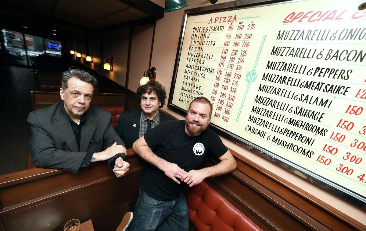 Left to right, Gorman Bechard, Dean Falcone and Colin Caplan are photographed in Modern Pizza in New Haven next to a pizza menu from the 1950's on Wednesday. They are raising funds for a documentary, "Pizza, A Love Story."