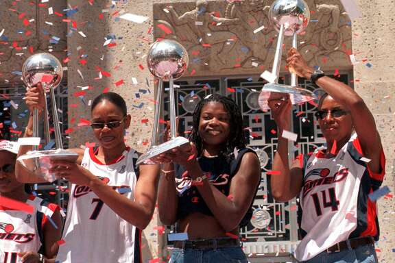 Houston Comets players Tina Thompson, left, Sheryl Swoopes, center, and Cynthia Cooper hoist the Comets' three WNBA championship trophies during a rally after a parade honoring the three-time WNBA champions Wednesday, Sept. 8, 1999, in Houston. (AP Photo/Brett Coomer)