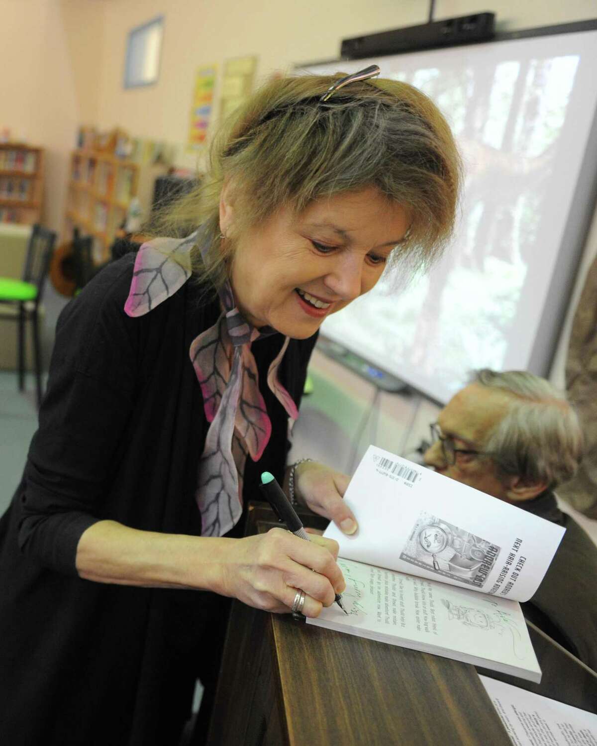 Author Judith (J.C.) Greenburg signs a copy of one of her book before speaking about the inspiration for her children's book at Cos Cob School in the Cos Cob section of Greenwich, Conn. Tuesday, Jan. 23, 2018. Judith Greenburg pens the "Andrew Lost" series. Also speaking was her husband, Dan Greenburg, author of the "Zack Files" and "Weird Planet" series.